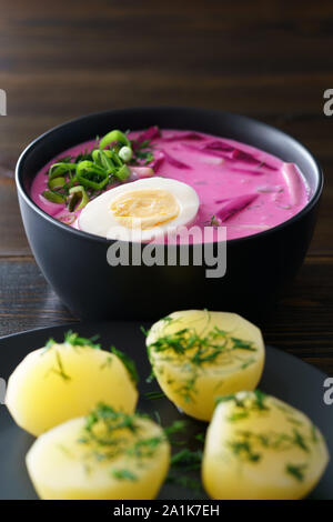 Il lituano Saltibarsciai (Freddo zuppa di barbabietole) con uovo sodo e patate condito con cipolline e aneto. Dark tavolo in legno, ad alta risoluzione Foto Stock