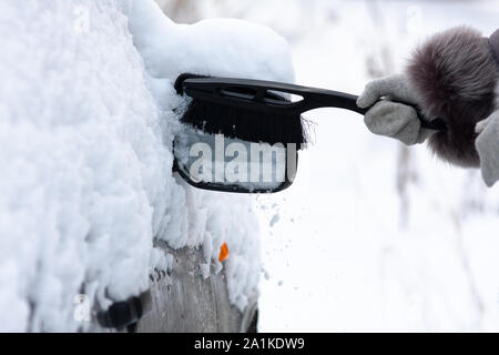 Mano nel guanto di pulizia auto da neve con una spazzola Foto Stock