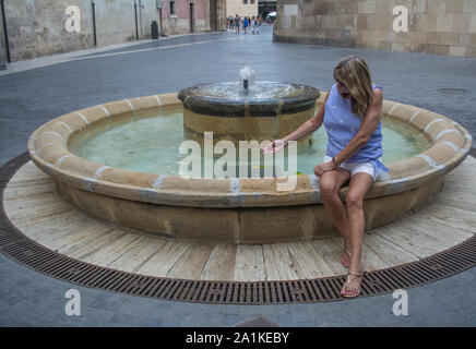 Femmina cali turistica la sua mano in una fontana di acqua nella città di Murcia Spagna Foto Stock