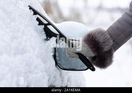 Mano nel guanto di pulizia auto da neve con una spazzola Foto Stock