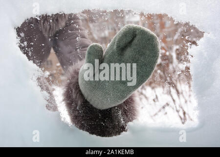 Mano nel guanto di pulizia della finestra auto da neve, vista interna Foto Stock