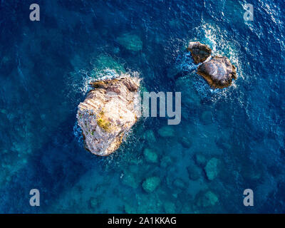 Vista aerea di un fondale con rocce emergenti dal mare, fondali visto dal di sopra, di acqua trasparente Foto Stock