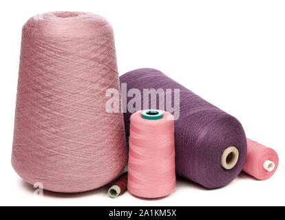 Gruppo di rocche e rocchetti di rosa e viola sintetico o fili di cotone isolati su sfondo bianco utilizzati per la tessitura nella produzione tessile Foto Stock