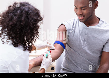 Close-up di medico tenendo campione di sangue dal braccio del paziente Foto Stock