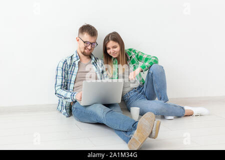 Affascinante giovane donna e un uomo sorridente sta guardando i negozi online utilizzando un computer portatile per acquistare impianti idraulici in un nuovo appartamento. Inaugurazione della casa nuova e il concetto di riparazione. Foto Stock
