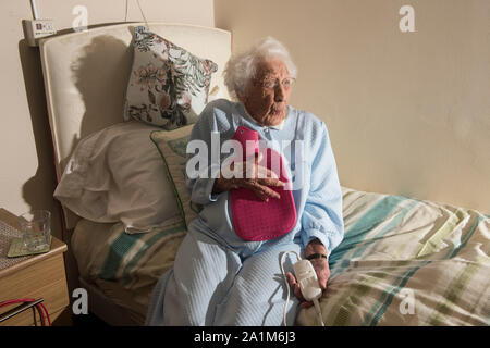 Signora anziana per andare a letto con una coperta elettrica e bottiglie di acqua calda la Gran Bretagna Regno Unito Foto Stock