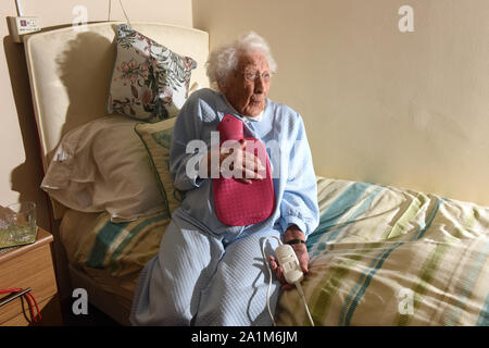 Signora anziana per andare a letto con una coperta elettrica e bottiglie di acqua calda la Gran Bretagna Regno Unito Foto Stock