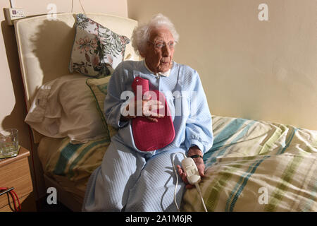 Signora anziana per andare a letto con una coperta elettrica e bottiglie di acqua calda la Gran Bretagna Regno Unito Foto Stock