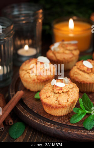 Senza glutine di zucca e muffin alla carota decorata con mandorle scure sul tagliere di legno. La Giornata del ringraziamento dessert Foto Stock