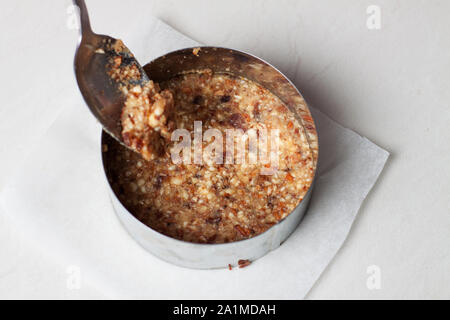 Materie vegan cheesecake preparazione. Noci frantumate in tondo anello metallico Foto Stock