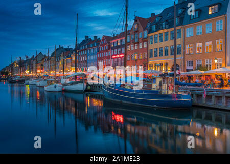 Una vista serale di colorate case a schiera lungo un canale nel quartiere di Nyhavn di Copenhagen, Danimarca. Foto Stock