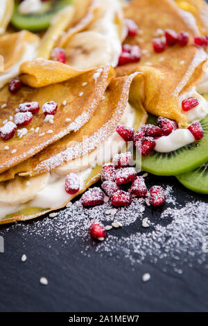 Crespelle sottili con il cioccolato fuso, i semi di sesamo, melograno e mandorle Foto Stock