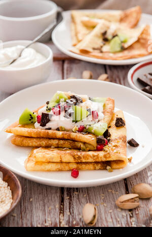 Crespelle sottili con il cioccolato fuso, i semi di sesamo, melograno e mandorle Foto Stock