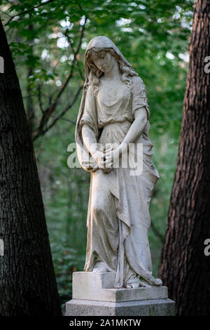 Statua di Pietra di un lutto donna come decorazione su un ombroso cimitero nel bosco Foto Stock