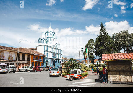 Case colorate e una chiesa bianca e blu intorno alla piazza principale di Filandia, una tipica città colombiana nella regione del caffè Quindio Foto Stock