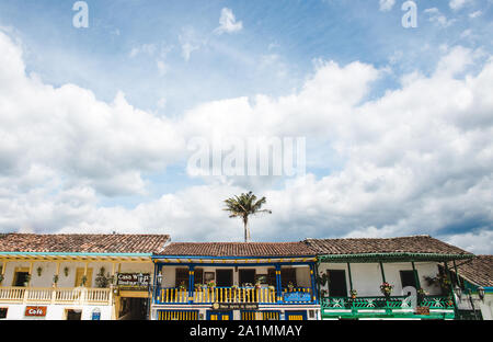 Lone palma dietro fila di case tradizionali colorate sulla piazza principale del Salento, una tipica città colombiana nella regione del caffè Quindio, popolare Foto Stock