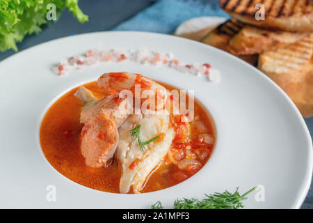 La dieta di zuppa di pesce e frutti di mare e pesci di diverse varietà in una piastra bianca. Close up. Foto Stock