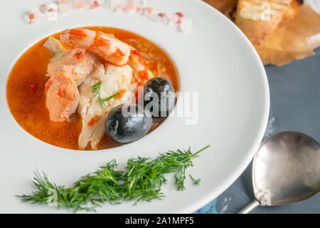 La dieta di zuppa di pesce e frutti di mare e pesci di diverse varietà in una piastra bianca. Close up. Foto Stock