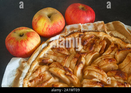 In casa crostata di mele su un piatto e tre mele Foto Stock
