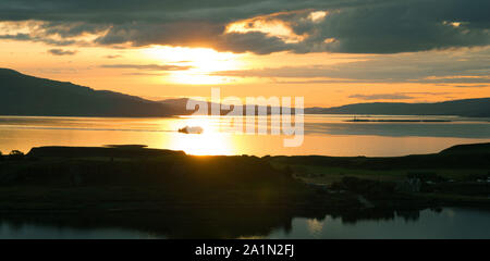 Tramonto sul mare dal pulpito Hill, Oban. Costa ovest della Scozia. Isola di Kerrera in primo piano e traghetto barca a vela da Isle of Mull retroilluminato in backgroun Foto Stock