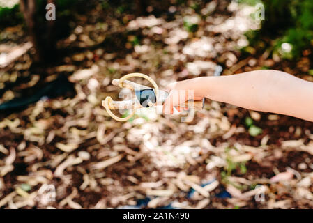 Bambino che gioca con la sua fionda in un parco divertimento in libertà. Foto Stock