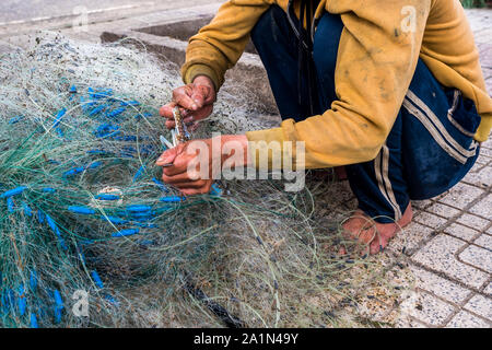 Le mani del vecchio pescatore spescano le reti da pesca, Nha Trang Foto Stock