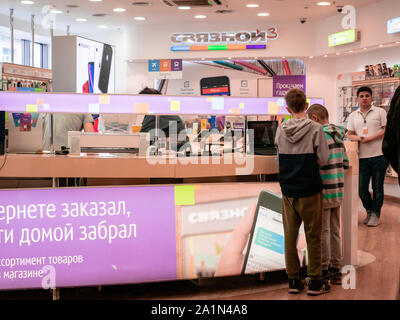 Mosca, Russia - 14 Settembre 2019: ragazzi a esaminare un laptop e altri prodotti in una vetrina di una comunicazione mobile e gadget. Dietro il Foto Stock