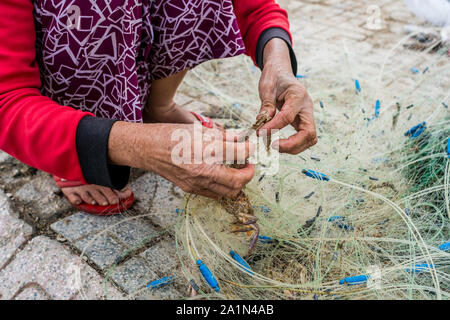 Le mani del vecchio pescatore spescano le reti da pesca, Nha Trang Foto Stock