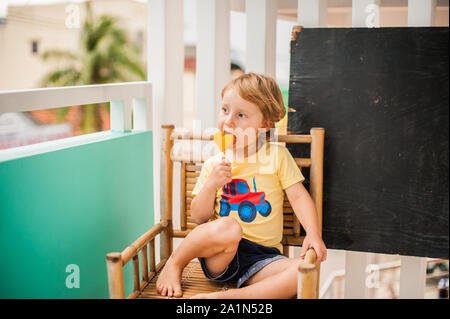 Ragazzo che beve frullato papaya. Concetto di cibo sano. Tavola di legno nero con spazio per il testo Foto Stock