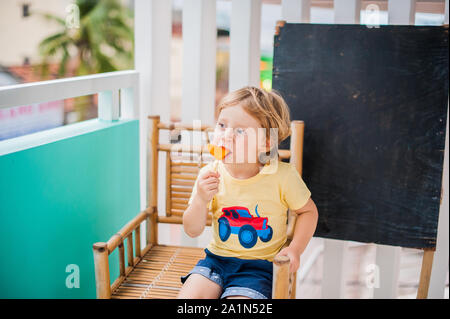 Ragazzo che beve frullato papaya. Concetto di cibo sano. Tavola di legno nero con spazio per il testo Foto Stock