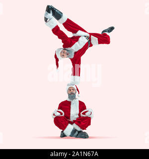 Felice Natale Santa Claus su coral di sfondo per studio. Caucasica modello maschile in vacanza tradizionale costume del. Concetto di vacanze, Capodanno, umore invernale, doni. Sorprendente, vendite. Fare trucchi. Foto Stock