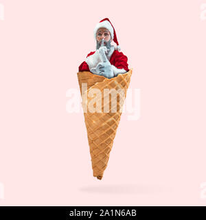 Felice Natale Santa Claus su coral studio sfondo come un gelato. Caucasica modello maschile in vacanza tradizionale costume del. Concetto di vacanze, Capodanno, umore invernale, doni. Le vendite. Foto Stock