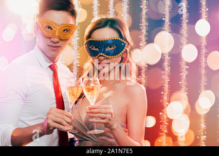 Coppia giovane per celebrare il nuovo anno e di bere champagne su masquerade party Foto Stock