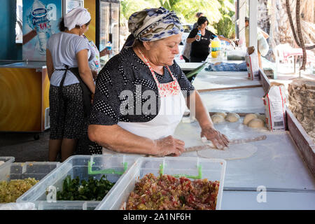 Alacati, Turchia - 7 Settembre 2019: Turco donna fare focacce su un mercato in stallo, il mercato si tiene ogni Sabato. Foto Stock