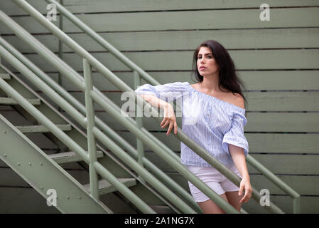 Bella giovane donna accanto alla scala industriale sui backstreet Foto Stock