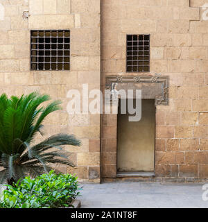 Esterno antico vecchi mattoni decorata muro di pietra con due finestre e porta aperta che conduce al periodo ottomano Beit El Sehemy edificio storico, il Cairo, Egitto Foto Stock