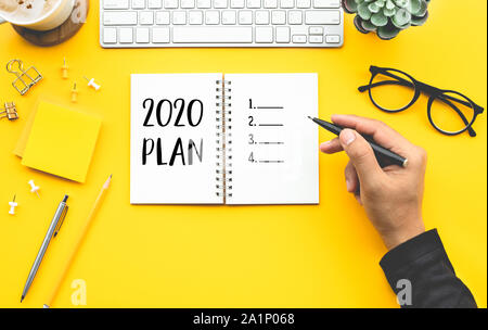Piano 2020 concetti con youngman elenco di controllo per la scrittura su notepad sul banco di colore tabella.Meta-plan-azione e concetti di risoluzione le idee Foto Stock