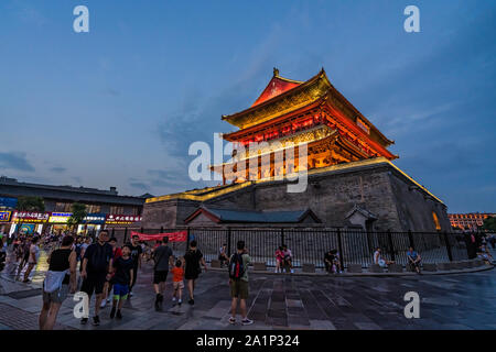 Xian, Cina - Luglio 2019 : i turisti a piedi nella parte anteriore della campana della Torre del Tamburo splendidamente illuminate e illuminata di notte, Shaaxi Provincia, Cina Centrale Foto Stock