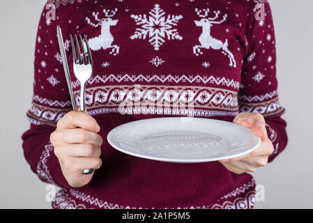 In attesa di una gustosa cucina casalinga concetto di nutrizione. Ritagliato close up foto di donna felice con forcella di supporto coltello e piastra bianca con le mani per chiedere Foto Stock