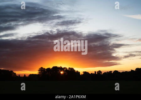 Chiesa di Woodstock e alberi silhouette a sunrise dal palazzo di Blenheim park. Oxfordshire, Inghilterra Foto Stock