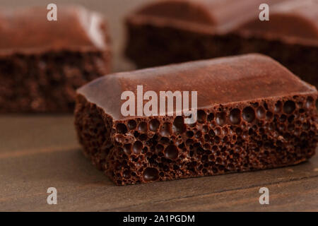 Pezzetti di cioccolato isolato su un tavolo di legno cubo poroso close-up Foto Stock