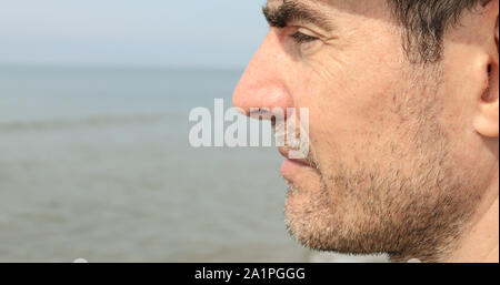 Molto vicino profilo di una mezza età barba lunga uomo caucasico guardando il mare. Foto Stock