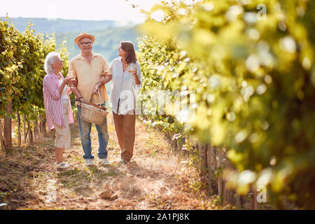 Maturazione delle uve in vigna vigneto di famiglia. La famiglia felice la tostatura e di bere il vino e divertimento all'aperto Foto Stock