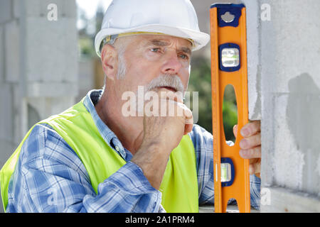 Un senior operaio parete di livellamento Foto Stock