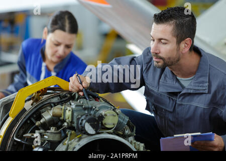 Apprendista studiando i motori delle auto con un meccanico Foto Stock