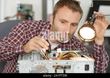 Uomo che fissa il computer mettendo la cpu su socket Foto Stock