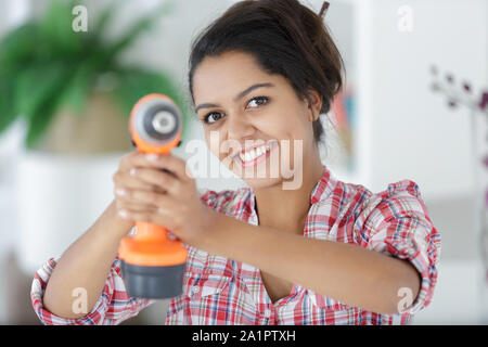 Donna felice utilizzando un trapano elettrico Foto Stock