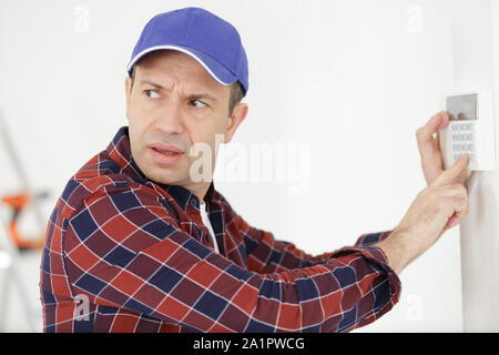 Gli uomini regola la temperatura sulla parete Foto Stock