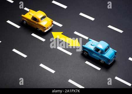 Due automobili giocattolo sulla strada una dopo l'altra. Uno è blu è colorata in giallo. Foto Stock