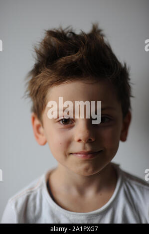 Ritratto di carino piccolo ragazzo con capelli tousled weating camicia bianca sorridente Foto Stock